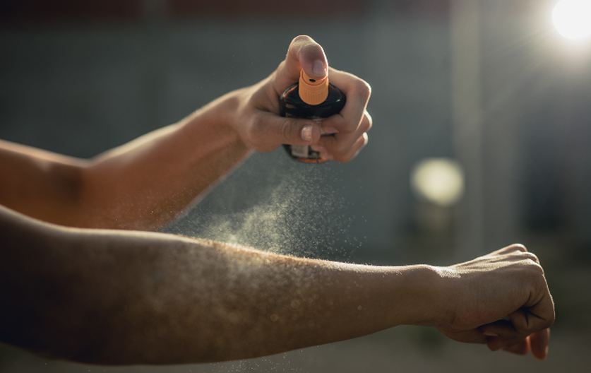 A person applying sunscreen spray